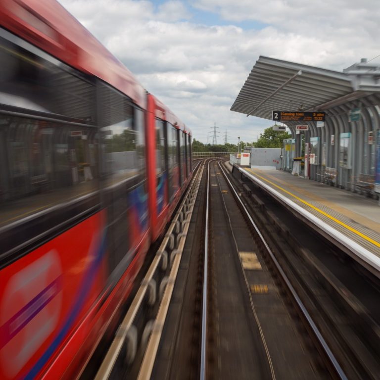 Photo of London gherkin building on the right and two construction cranes on the left. 
